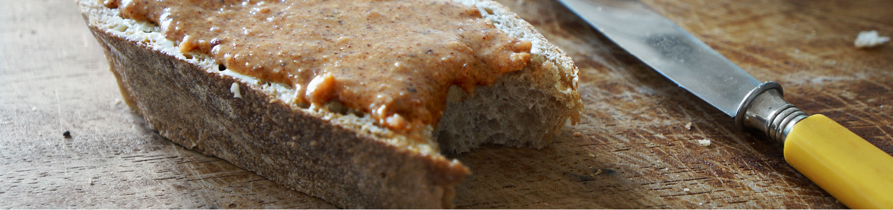 Angebissene Scheibe Brot mit Nusscreme "Mandelikat" von "Brandgut"