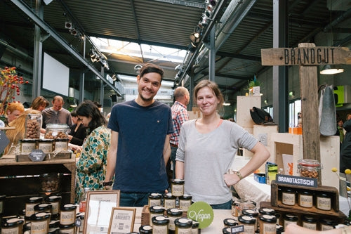 Zwei Menschen stehen an einem Stand, an dem Brandgut Nusscreme verkauft wird